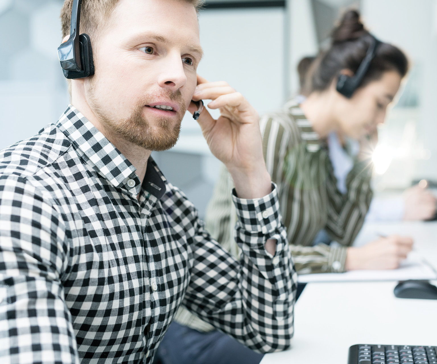 young man in black and white plaid shirt on phone offering ERP Support Services from Strategic Information Group